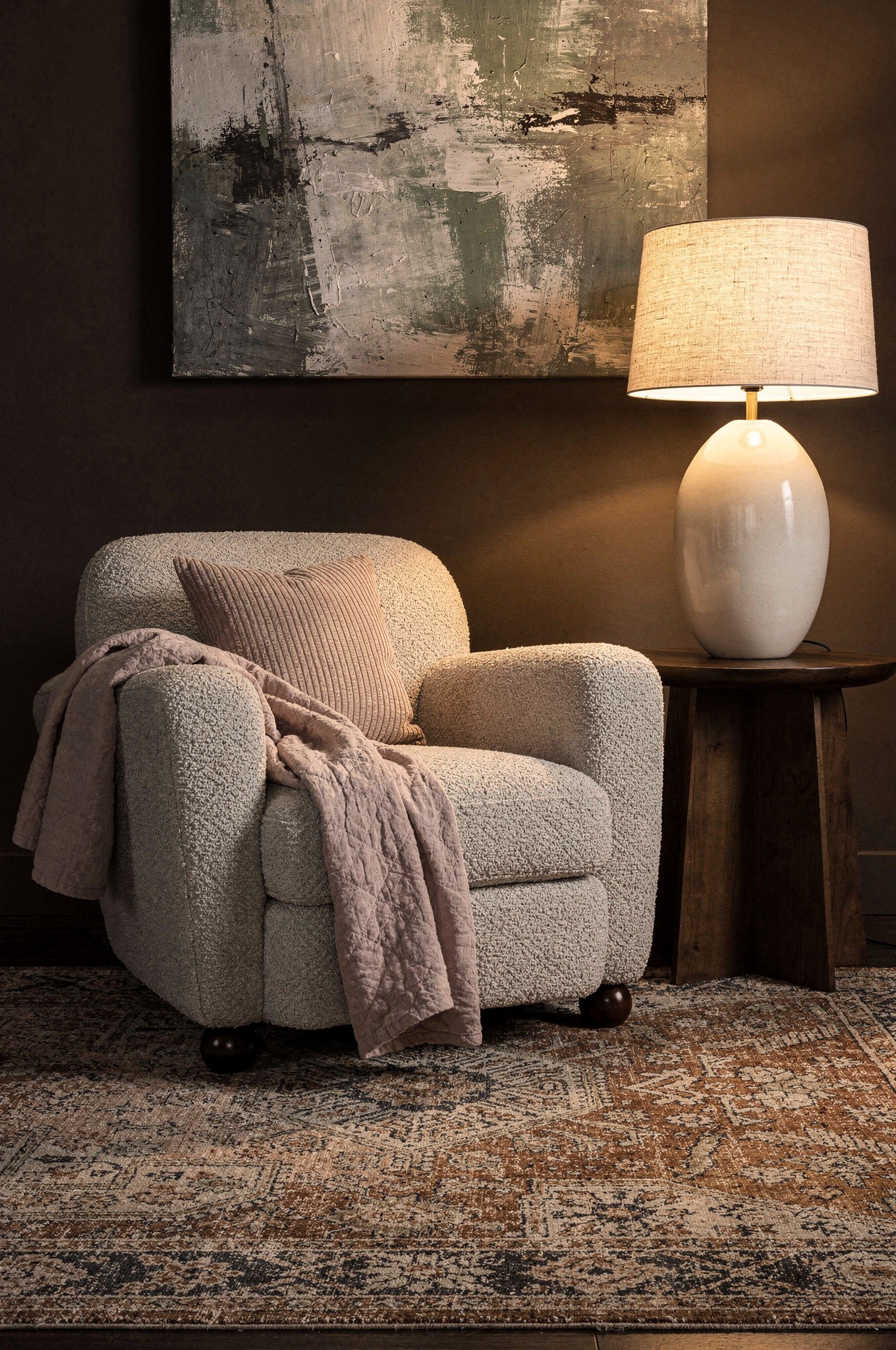 A cream bouclé armchair with a looped, nubbly texture beside a smooth linen sofa in warm afternoon light