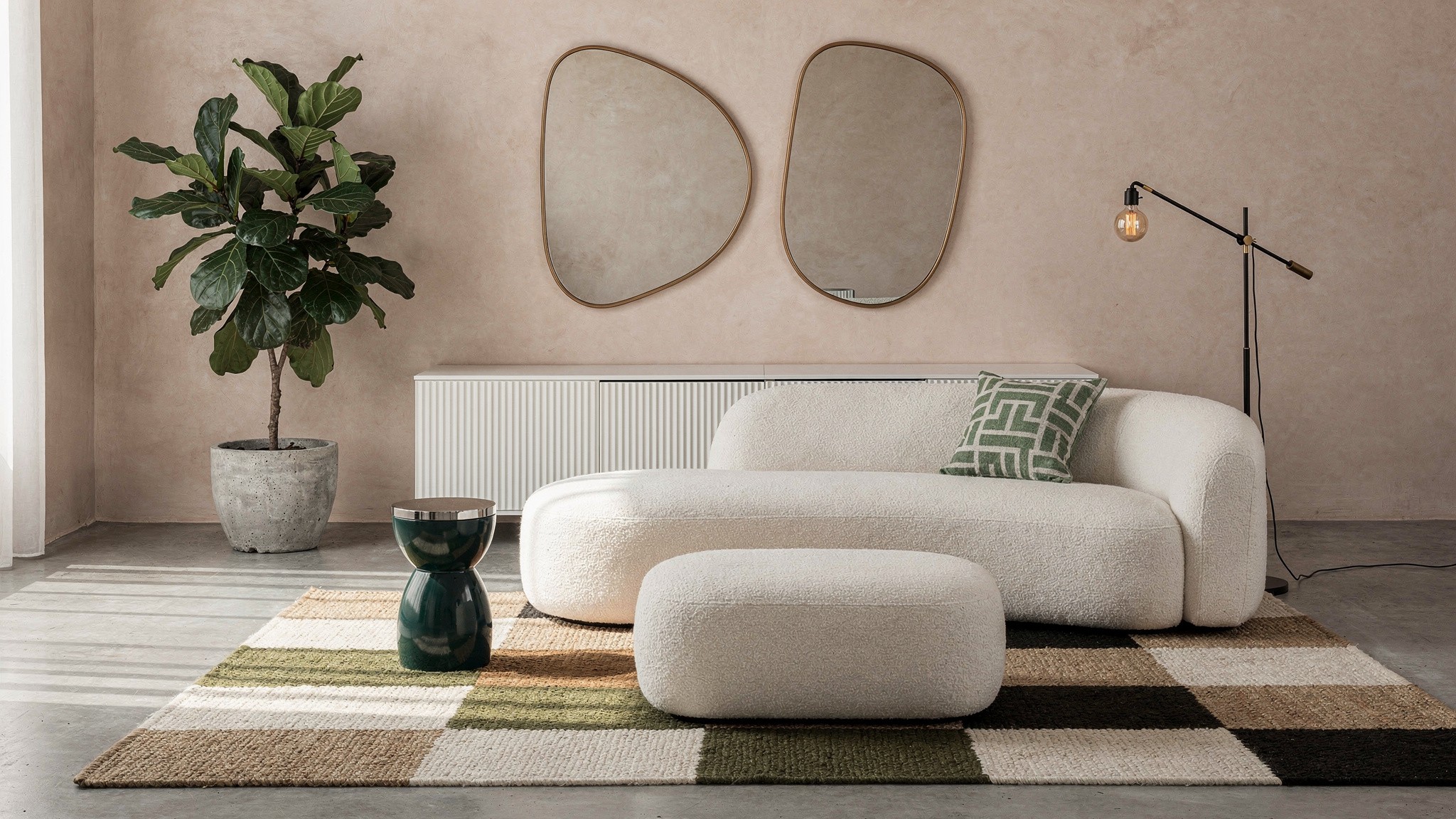 A cream bouclé sofa and matching ottoman on a striped wool rug, positioned as light-contact pieces rather than the main daily seating