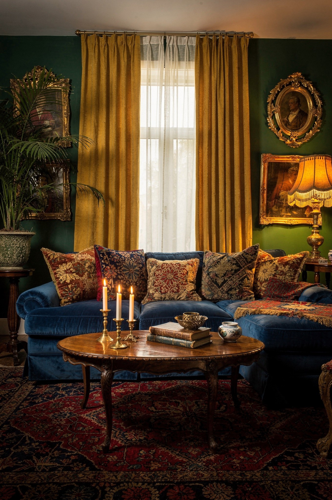 A jewel-tone living room corner with rich velvet upholstery, brass lighting and warm candlelight