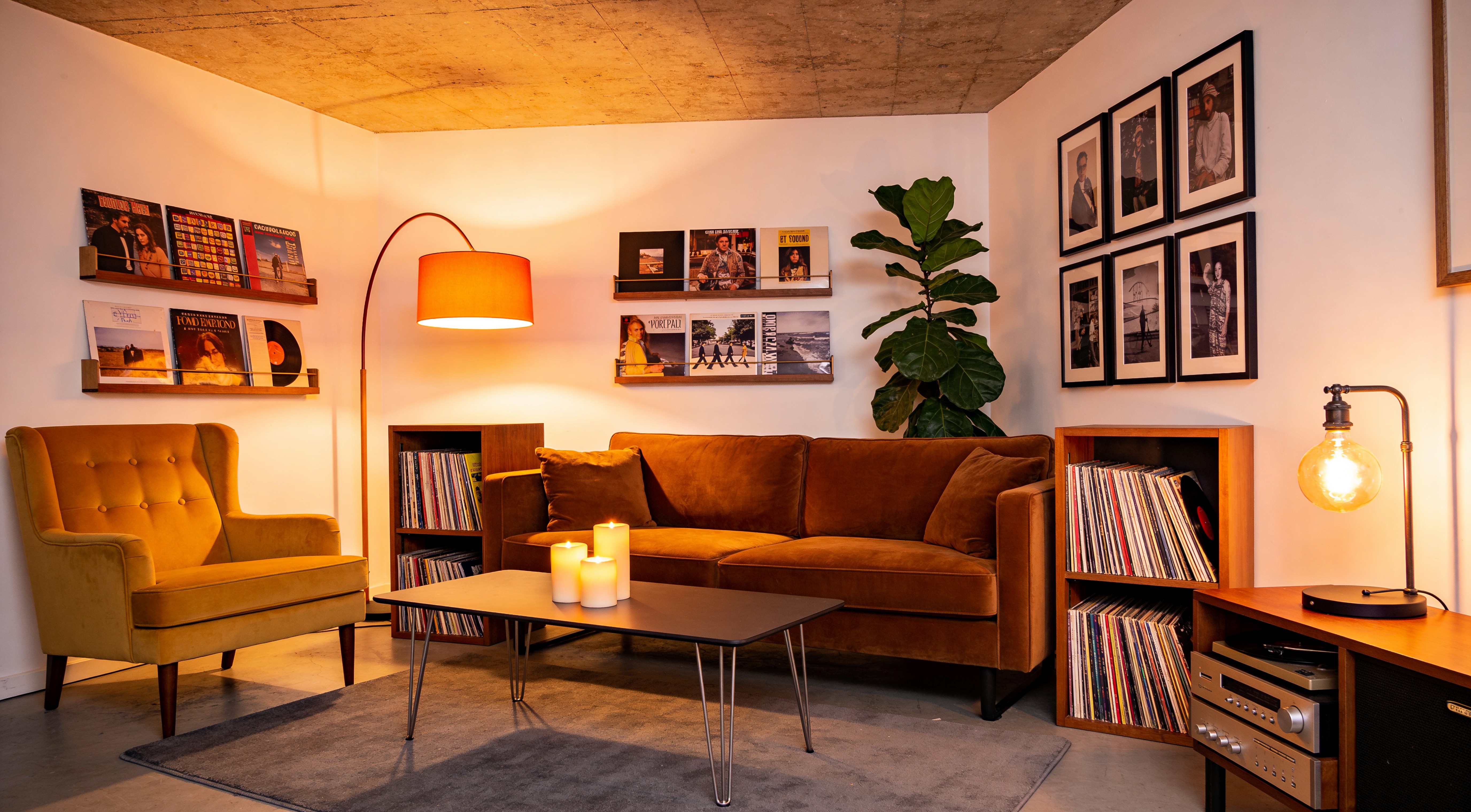 Your moody, warm living room at night with layered lighting, a green bouclé chair, vinyl record wall and city view