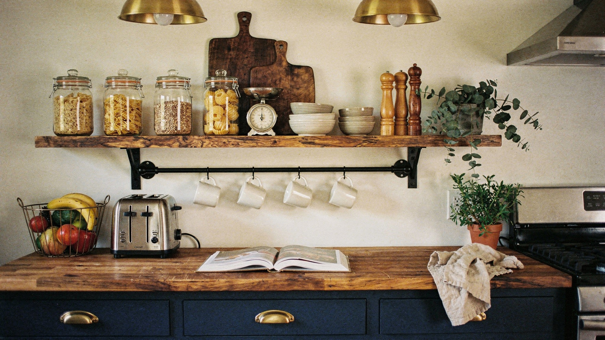 A kitchen with open oak shelving holding neatly arranged ceramics above a run of closed lower cabinets